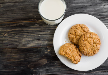 Oatmeal cookies with milk on a wooden table in rustic style