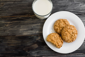 Oatmeal cookies with milk on a wooden table in rustic style
