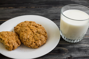 Oatmeal cookies with milk on a wooden table in rustic style