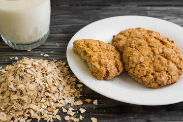 Oatmeal cookies with milk and ingredients on a wooden table in rustic style