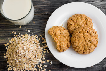 Oatmeal cookies with milk and ingredients on a wooden table in rustic style