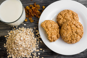 Oatmeal cookies with milk and ingredients on a wooden table in rustic style