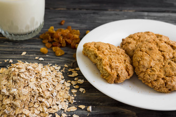 Oatmeal cookies with milk and ingredients on a wooden table in rustic style