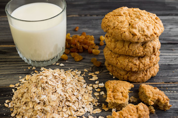 Oatmeal cookies with milk and ingredients on a wooden table in rustic style
