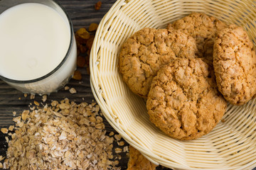 Oatmeal cookies with milk and ingredients on a wooden table in rustic style