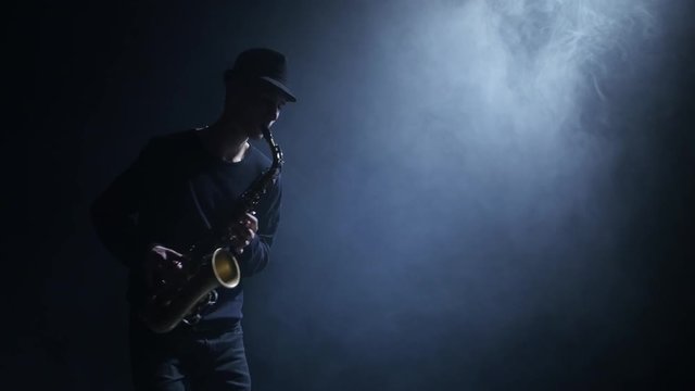 Bluesman performing compositions on the saxophone. Smoke in the dark