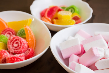 Multicolored fruit candy and marshmallow in a white bowl. Delicious and beautiful dessert.