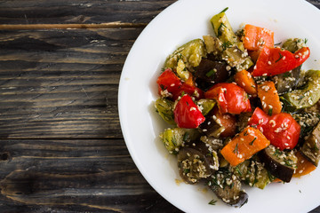 Baked vegetables with sesame seeds on a wooden background in rustic style