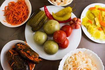 Pickled tomatoes and other vegetables in white bowls