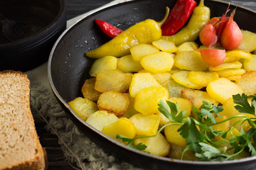 Fried potatoes in a pan with pickled vegetables