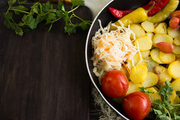 Fried potatoes in a pan with pickled vegetables
