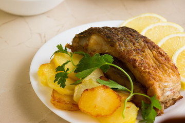 Fried carp with fried potatoes on a white plate