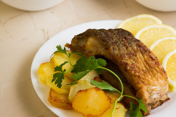 Fried carp with fried potatoes on a white plate