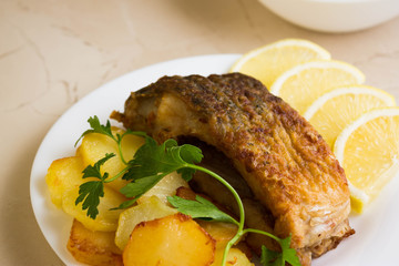 Fried carp with fried potatoes on a white plate