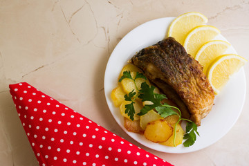 Fried carp with fried potatoes on a white plate