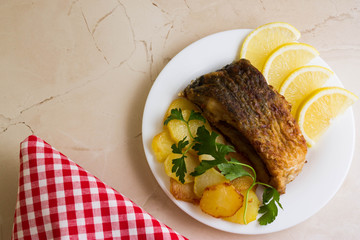 Fried carp with fried potatoes on a white plate