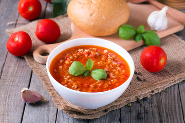 Tomato soup and fresh tomatoes on a wooden background