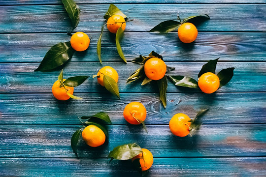Tangerines with leaves on blue wooden table.
