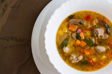 Vegetable soup with chicken giblets in a white bowl on a marble table