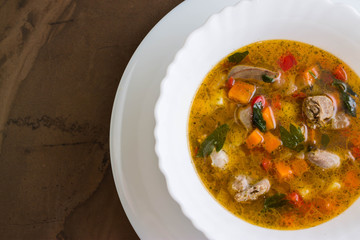 Vegetable soup with chicken giblets in a white bowl on a marble table