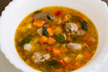 Vegetable soup with chicken giblets in a white bowl on a marble table