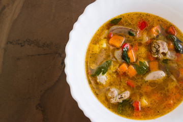 Vegetable soup with chicken giblets in a white bowl on a marble table