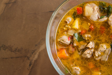 Vegetable soup with chicken giblets in a glass bowl on a marble table
