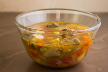 Vegetable soup with chicken giblets in a glass bowl on a marble table