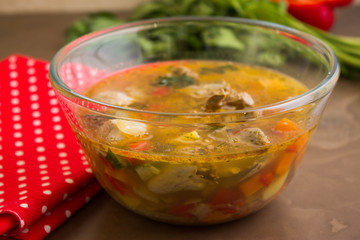Vegetable soup with chicken giblets in a glass bowl on a marble table