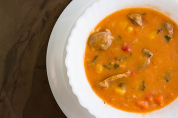 Tomato soup with chicken giblets in a white bowl