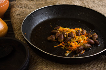 Fried chicken hearts with vegetables on a frying pan