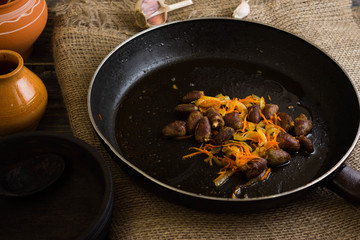 Fried chicken hearts with vegetables on a frying pan