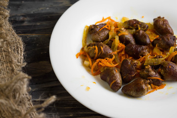 Fried chicken hearts with vegetables on a white plate