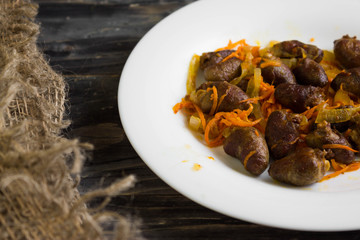 Fried chicken hearts with vegetables on a white plate