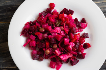 Beetroot salad in a white bowl on a wooden background in rustic style