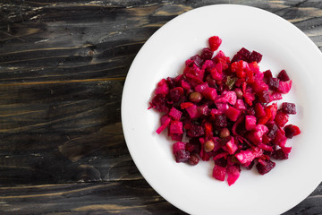 Beetroot salad in a white bowl on a wooden background in rustic style