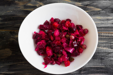 Beetroot salad in a white bowl on a wooden background in rustic style