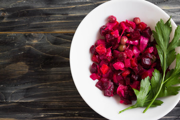 Beetroot salad in a white bowl on a wooden background in rustic style
