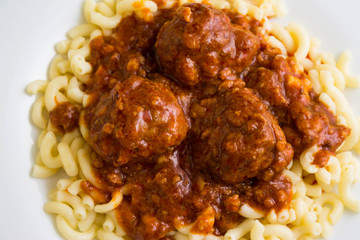 Meatballs in tomato sauce with pasta on a white plate