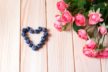 Beautiful roses and heart on a wooden background