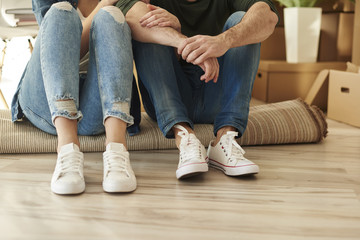 Low section of couple sitting on carpet