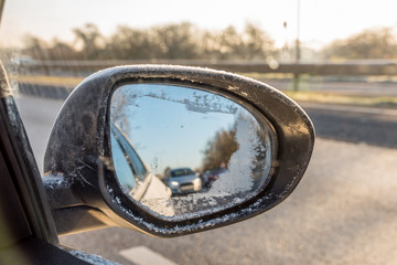 Back view through frozen car wing mirror on motorway