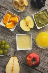 Baby mash food. Raw fruits next to puree. Top view.