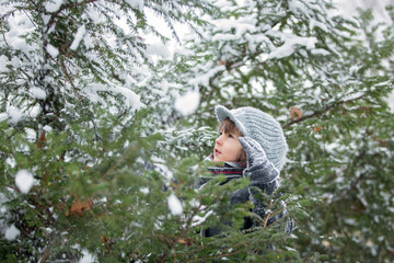 Naklejka na ściany i meble Happy little child, boy, playing outdoors in a snowy park