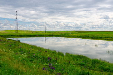 Small pond surrounded by green fields, rural landscape