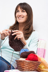 femme souriant qui tricote avec des aiguilles et des pelotes de laine