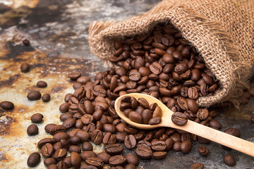 Roasted coffee beans in small sack on metal surface