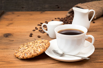 Cup of coffee with cookies, roasted coffee beans in sack