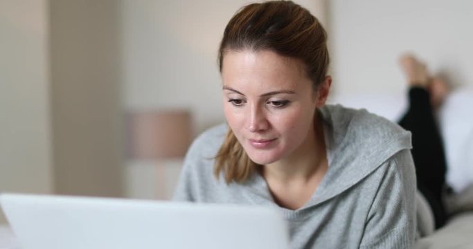 Young adult female using laptop in bed
