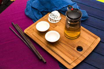 Green herbal tea in glass teapot on the blue wood background wit